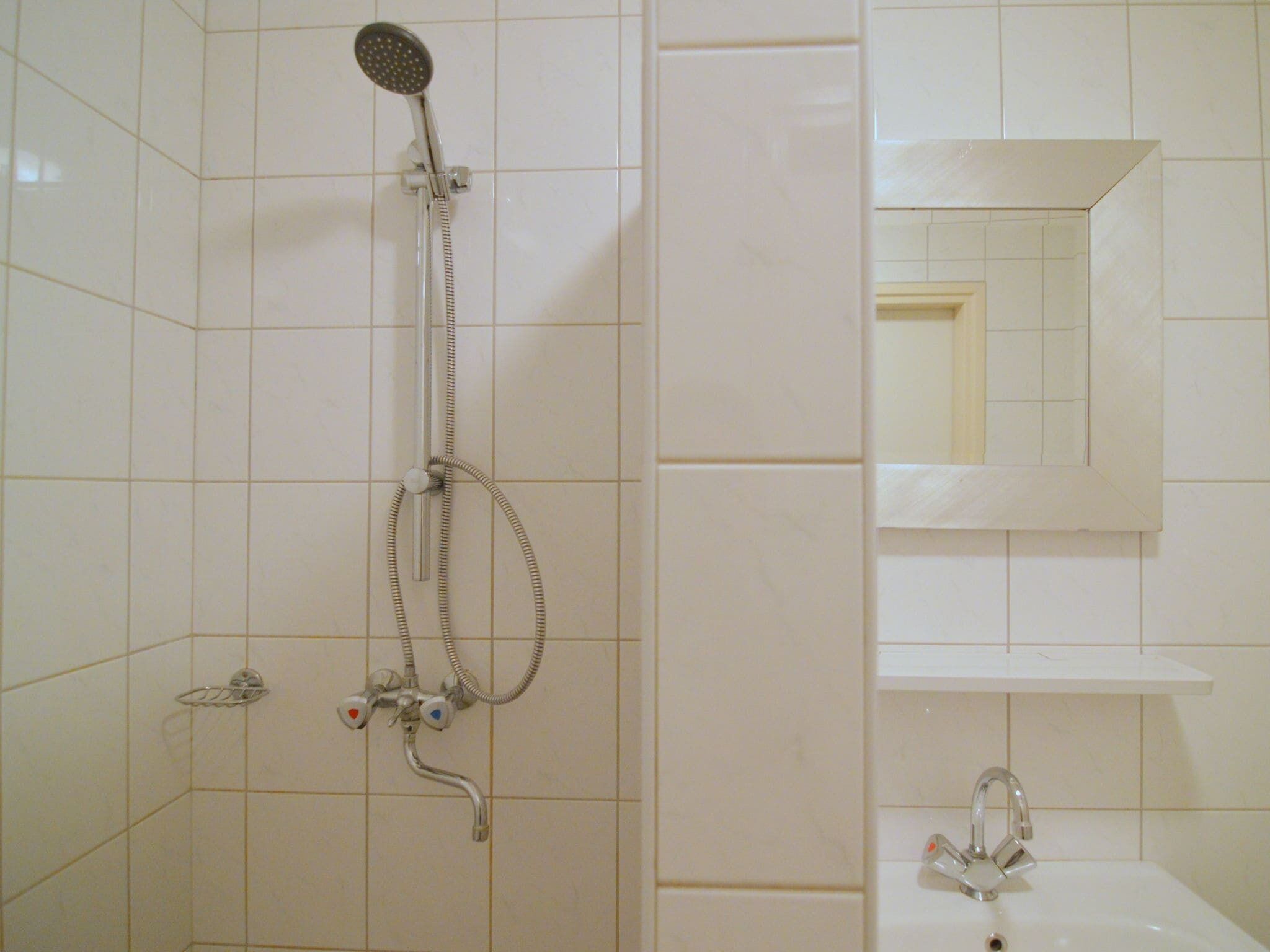 Un baño con ducha, lavamanos y espejo.