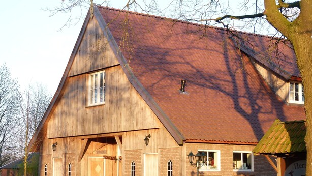 Un bâtiment en bois doté d’un toit en pente, d’une porte en bois et d’un banc à l’extérieur.