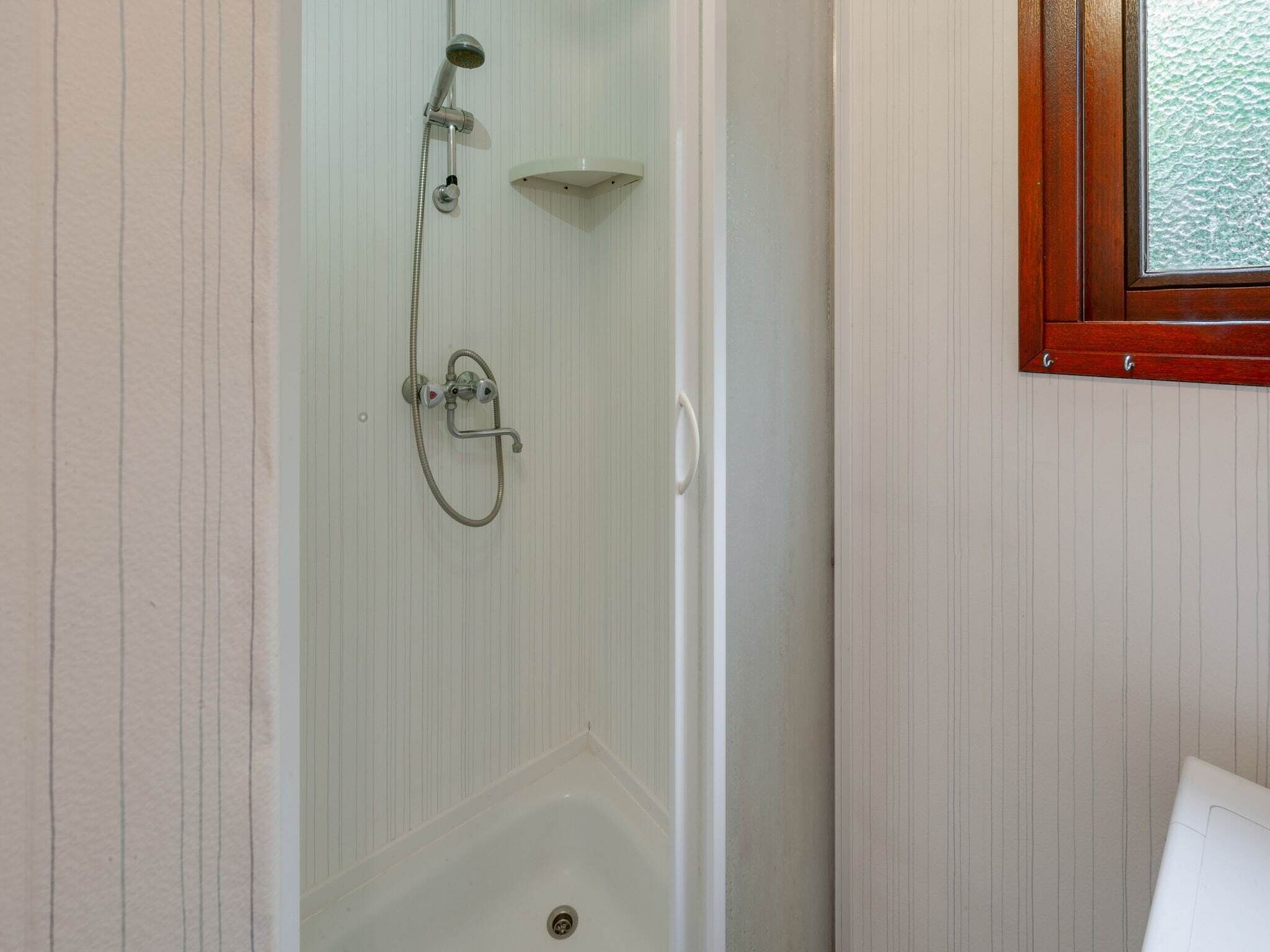 A shower with a handheld showerhead and a wall-mounted faucet.