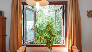 Een eettafel met een bloemenvaas, houten stoelen en een raam met gordijnen.