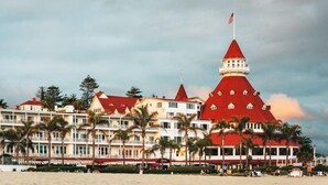 Ein großes Hotel mit mehreren Gebäuden mit roten Dächern, einem markanten Turm mit amerikanischer Flagge und einer Lage direkt am Strand.