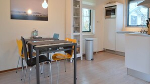 Una cucina moderna con mobili bianchi, forno integrato e una finestra con persiane.