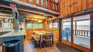 Interior de madera con una mesa de comedor, sillas y vistas al exterior.