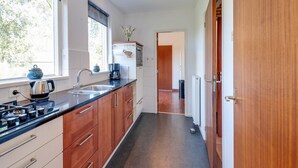 Una cocina moderna con armarios de madera, encimera negra y ventana con vistas a árboles.