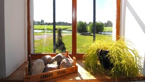 Ikkunasta avautuu näkymä vehreään maisemaan, ja siinä on näkyvillä puinen laatikko, jossa lukee teksti ”GERARD DUBOIS”, sekä kasa keltaista ruohoa.