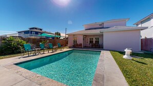 Ein Garten mit Schwimmbad, einer Holzterrasse und einem Haus.