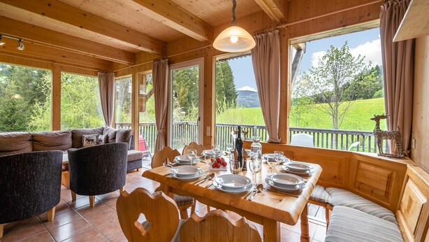 A wooden cabin with a dining area, a sofa, and a view of the outdoors. - Chalet in St. Georgen (St.Georgen ob Murau)