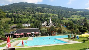 A swimming pool area with a view of a church and houses in the background. - Chalet in St. Georgen (St.Georgen ob Murau)