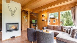A cozy cabin interior with a fireplace, wooden walls, a sofa, and a television. - Chalet in St. Georgen (St.Georgen ob Murau)