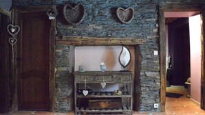 A rustic stone fireplace with a wooden mantel, surrounded by stone walls and a wooden door. - Champlon Villa near Forest (Champlon)