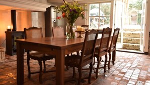 A wooden dining table with six chairs, a vase with flowers, and a candle holder. - Grand townhouse in Harlingen near Beach (Harlingen)