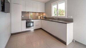 A modern kitchen with white cabinets, a built-in oven, a sink, and a window providing natural light.