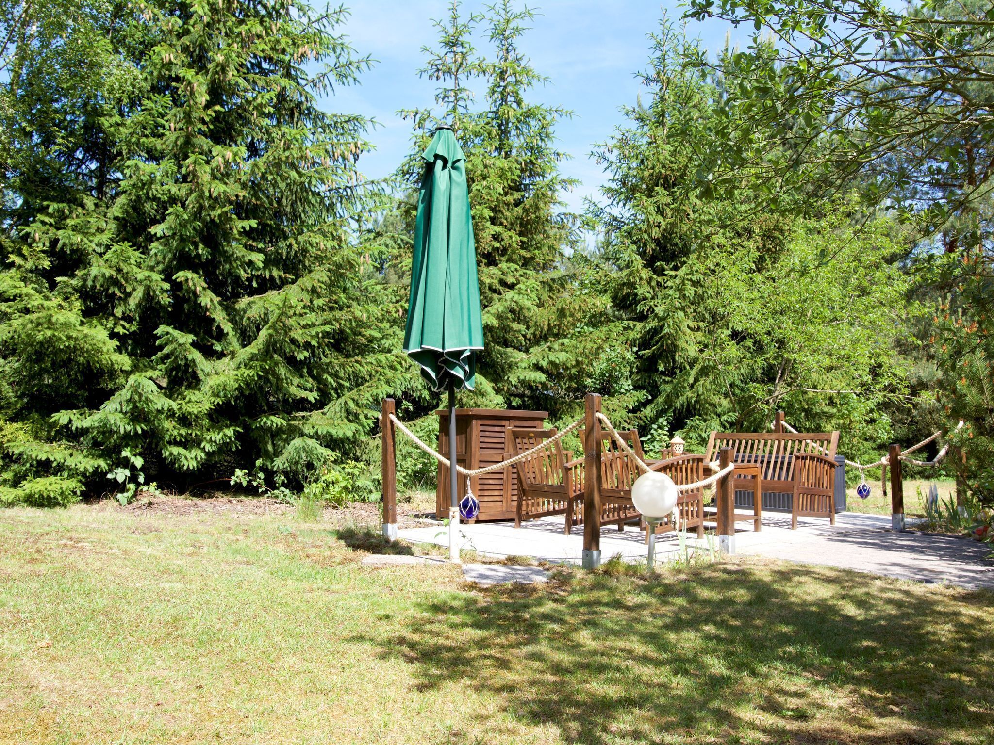 Un parque infantil con columpios y una estructura para escalar, rodeado de árboles frondosos.