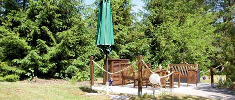 Un parque infantil con columpios y una estructura para escalar, rodeado de árboles frondosos.