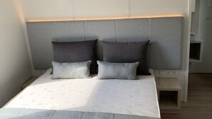 A bed with a headboard, two pillows, a bedside table, and a nightstand. - Auw Farm Life Escape (Auw)