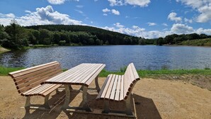 Two wooden benches facing a lake with a forested hill in the background. - Auw Farm Life Escape (Auw)
