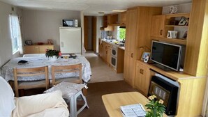 A compact RV interior with a kitchenette, dining area, and a small living space. - Auw Farm Life Escape (Auw)