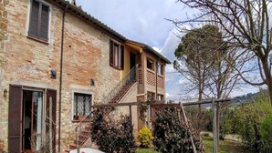 A rustic stone building with a balcony, a small table, and a chair outside.