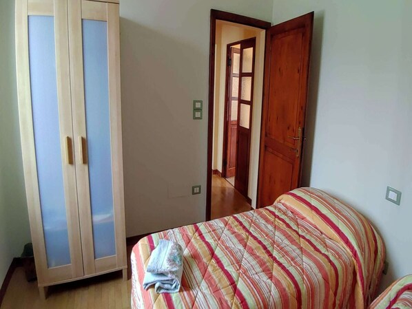 Un dormitorio con cama, armario y puerta que da a otra habitación.
