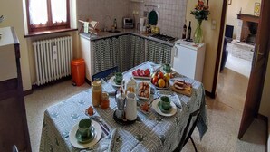 A kitchen with a dining table set for breakfast, a radiator, a small trash bin, and a view into the living area.