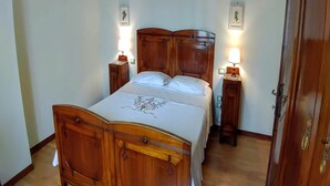 A wooden bed with a headboard, two bedside tables with lamps, and a door to the right.