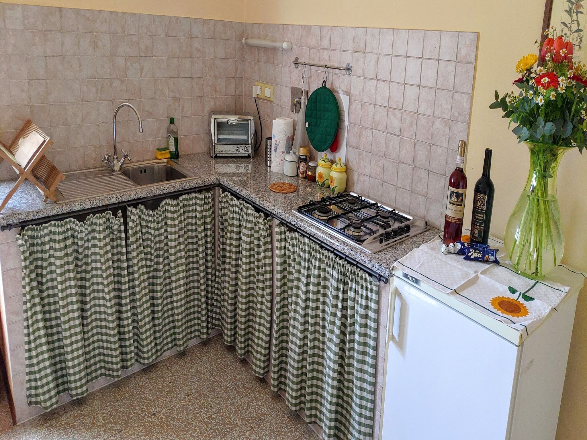 A kitchen with a sink, a toaster, a stove, and a refrigerator.