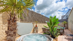 A hot tub in a backyard with a stone wall, a Buddha statue, and outdoor furniture. - Peaceful Getaway with Spa, Avelgem (Avelgem)