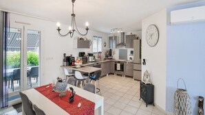 A modern kitchen with a dining area, a chandelier, and a clock on the wall. - Zen room in shared home with pool (owner-on site) (Saint-Médard de Guizières)