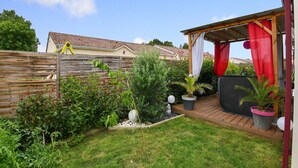 A backyard with a wooden deck, a covered seating area, and various plants. - Zen room in shared home with pool (owner-on site) (Saint-Médard de Guizières)