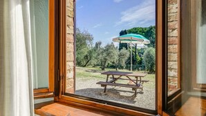 Vista a través de una ventana de un patio con una mesa de picnic y un paraguas verde.