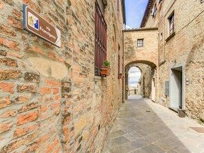 A narrow alleyway with stone walls, a sign indicating a location via Francigena, and an archway leading to a distant view. - Cozy Farmhouse with Pool (Gambassi Terme-Fi)