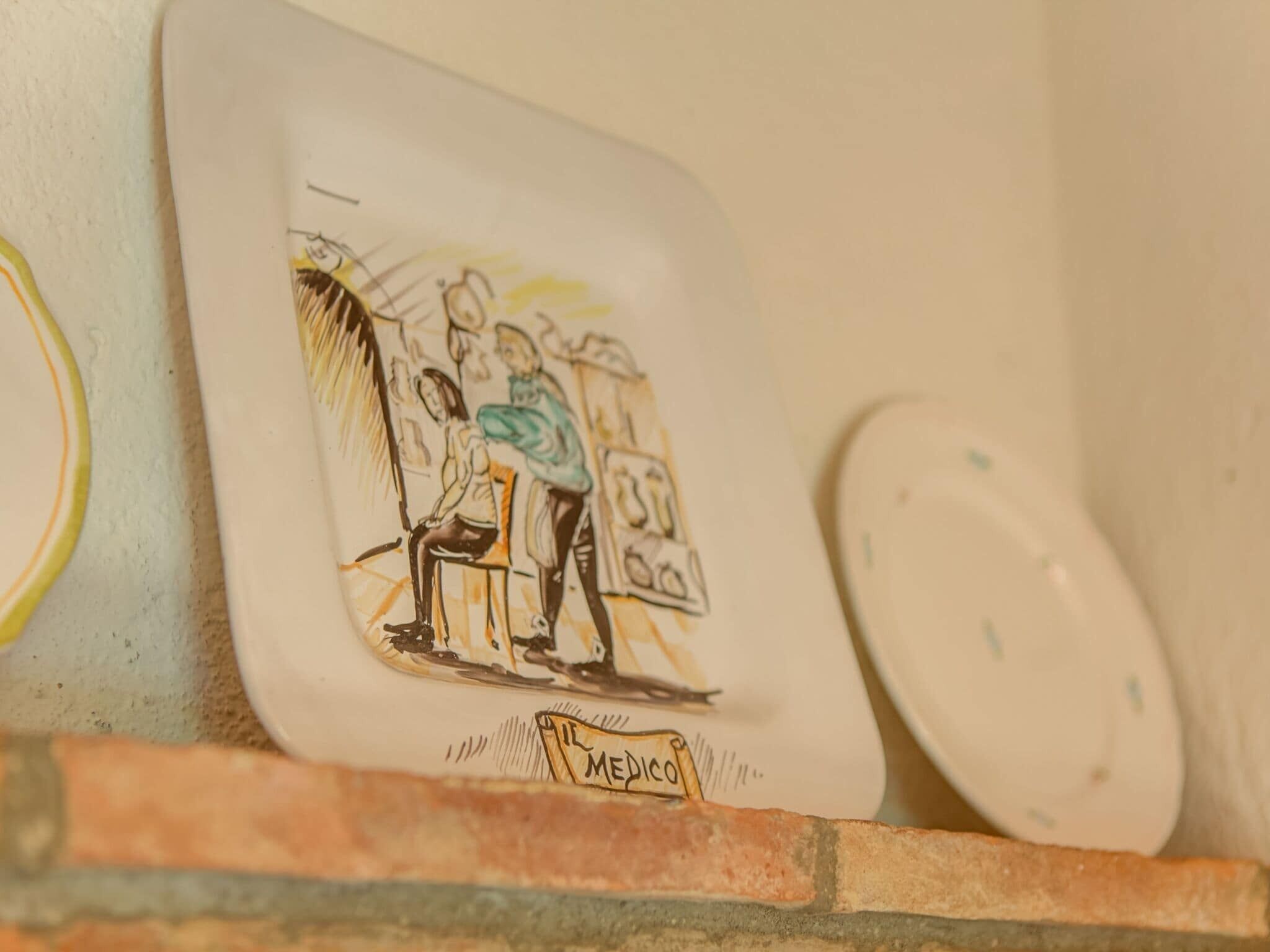 A wall-mounted plate with a drawing of a person sitting and another standing, labeled "Mexico."