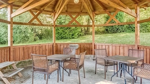 A covered patio with wooden beams and a view of a grassy area.
