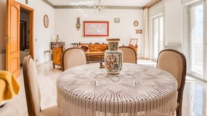 A dining room with a round table, chairs, a chandelier, and a decorative vase.
