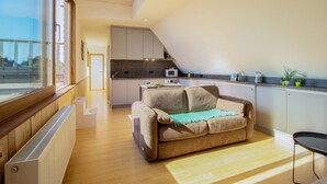 Um apartamento moderno com uma área de estar acolhedora, uma cozinha compacta e vista através de grandes janelas.