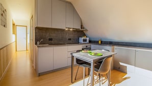 Cozinha moderna com armários cinzas, micro-ondas e mesa de jantar com cadeiras.
