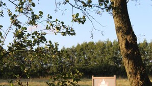 A sign with the text "ZON" and "WAKANTIWONG" in a rural setting with trees and a fence.