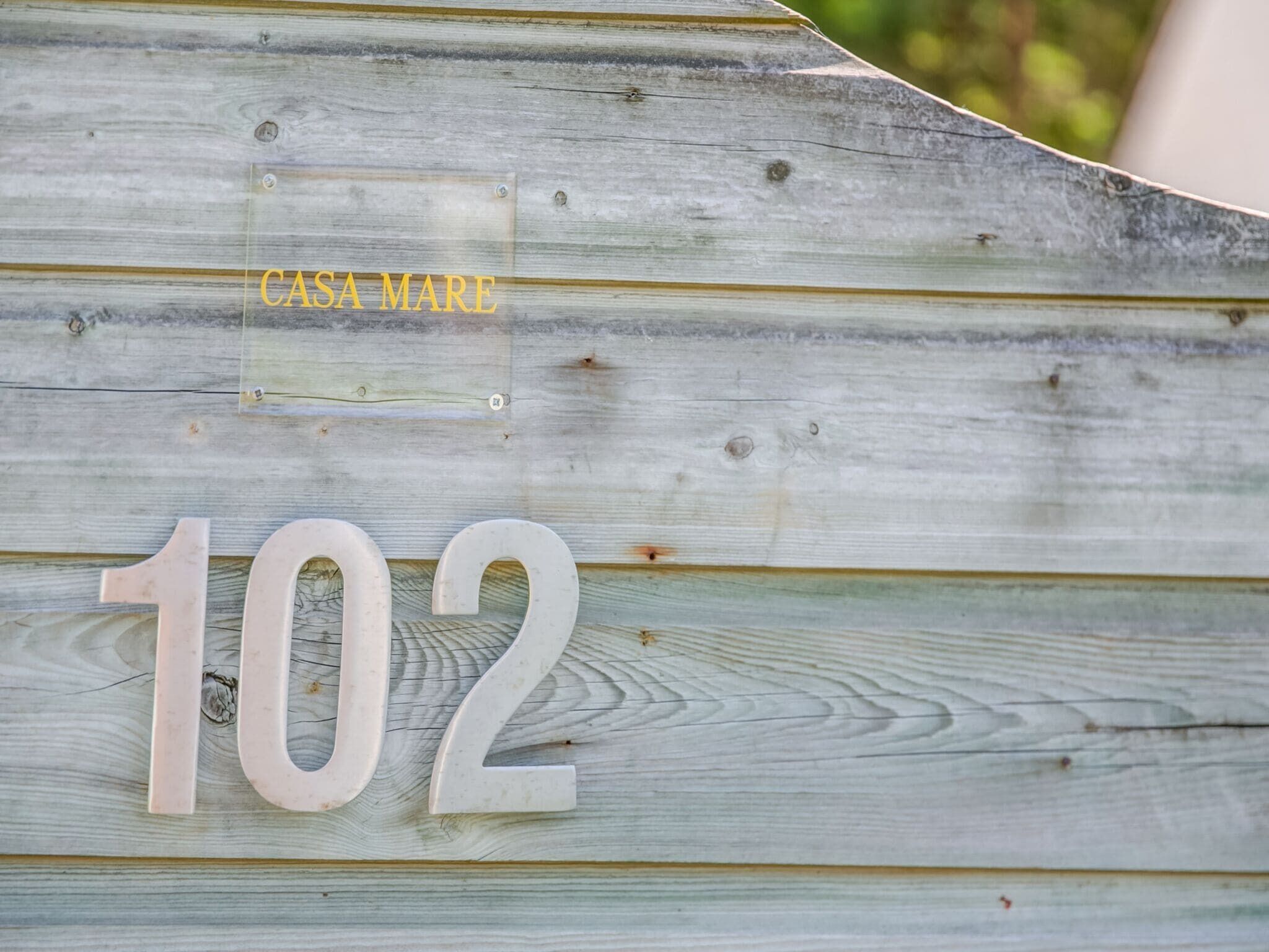Houten bord met het nummer 102 en de tekst 'CASA MARE', dat een eigendom of locatie aangeeft.