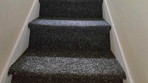 Eine Treppe mit Teppichstufen, die zu einer Zwischenebene führt.