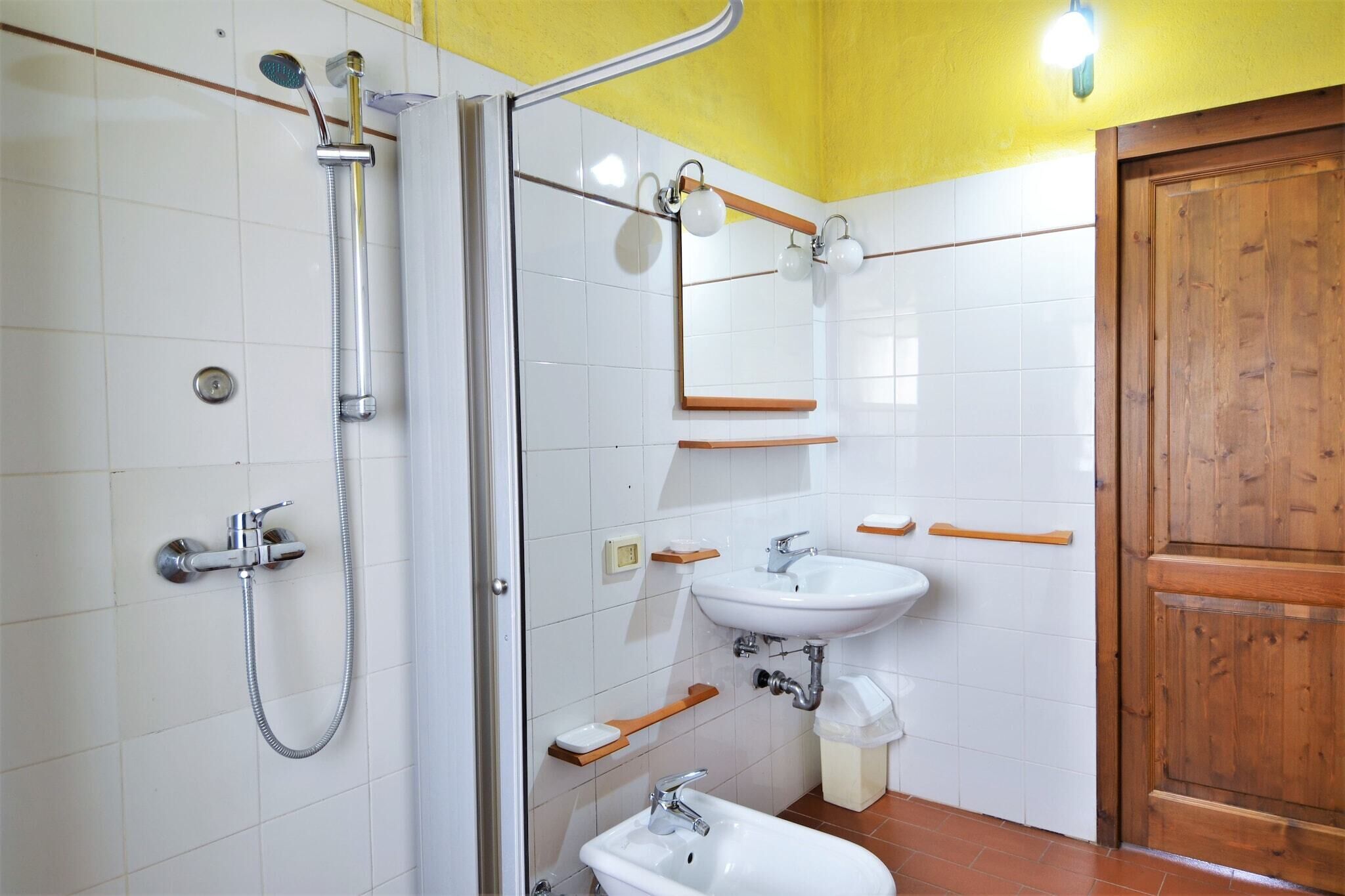 A bathroom with a shower, sink, and wooden door.