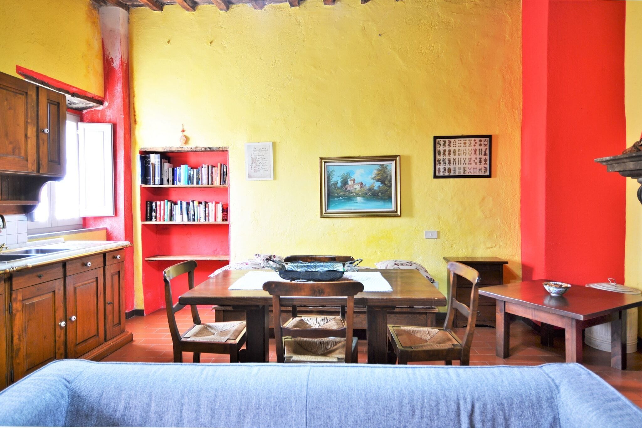 Een eetgedeelte met een houten tafel, stoelen en een boekenkast.