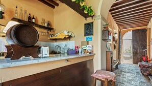 Una zona de bar con mostrador de madera, taburetes y una pizarra con la carta.