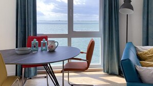 A room with a dining table, chairs, and a view of the sea through large windows. - Beautiful apartment with sea view (Scherpenisse)