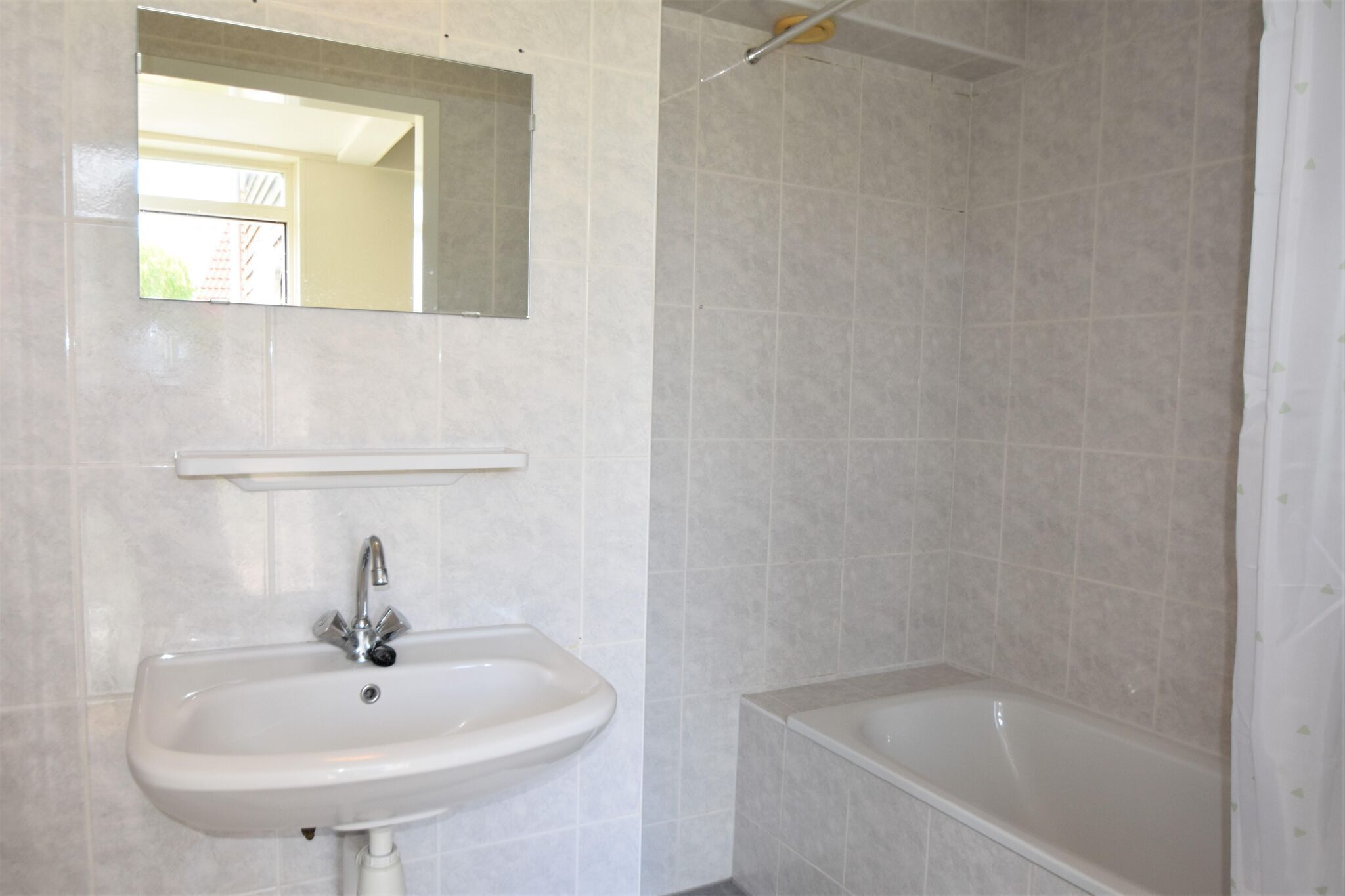 Un baño con lavabo, espejo y bañera.