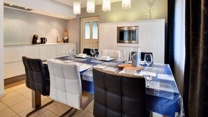 A modern dining area with a table set for four, a built-in oven, and pendant lights. - Charming holiday home with a covered terrace (Meijel)