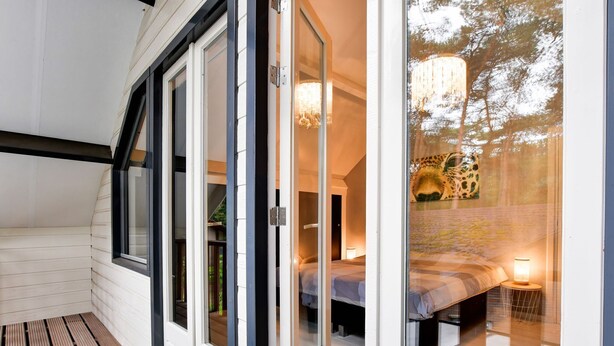 A modern bedroom with a sliding glass door leading to a balcony. - Charming holiday home with a covered terrace (Meijel)