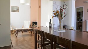 Een eethoek met een houten tafel en stoelen, een vaas met bloemen en een kruis aan de muur.