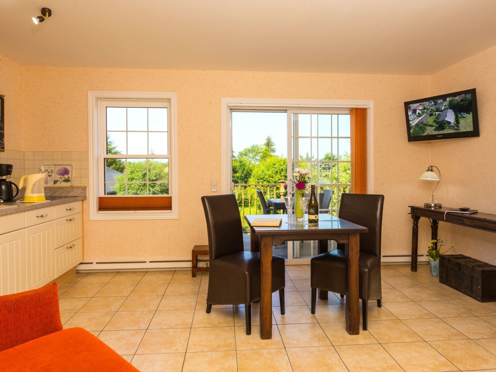 A dining area with a table and chairs, a kitchen area with a coffee maker, and a television on the wall.