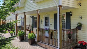 Ein Haus mit Veranda, Blumentöpfen und einem Holzzaun.