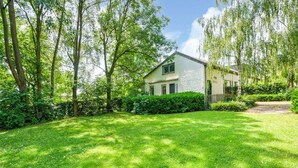Ein Haus mit weißer Fassade, umgeben von üppiger Vegetation und Bäumen.